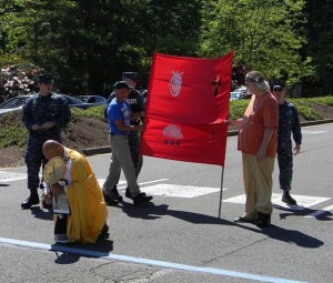 Photo by Leonard Eiger. Larry Kerschner (in red shirt), Br. Gilberto Perez, and Bernie Meyer (in blue shirt) blocking traffic onto the Bangor Trident base during their nonviolent direct action. 